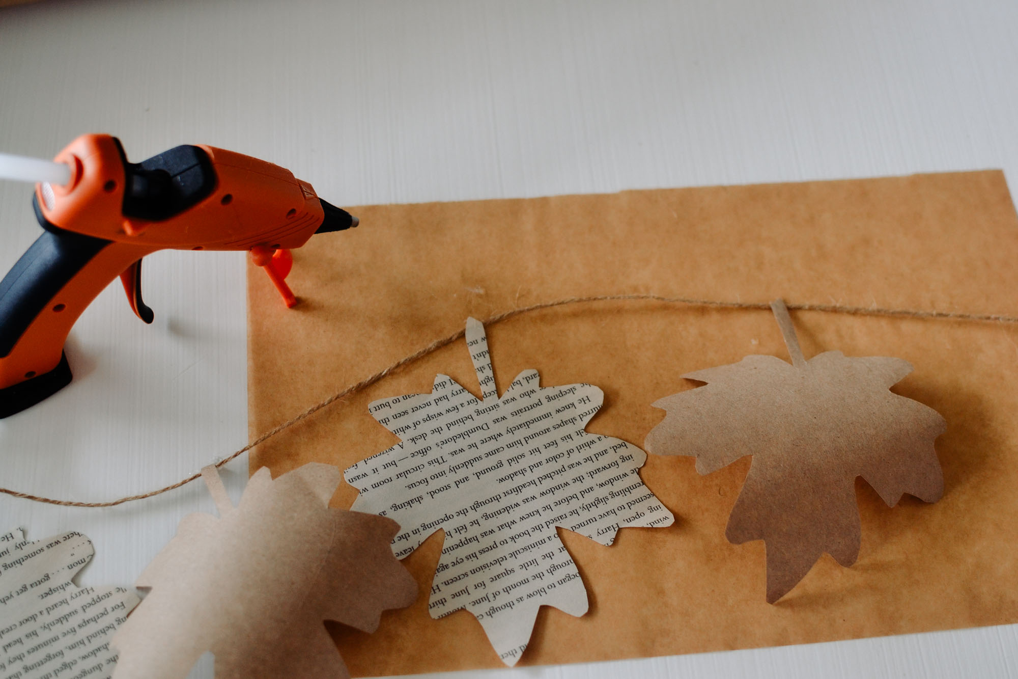 gluing paper leaves to twine, using parchment paper and a hot glue gun
